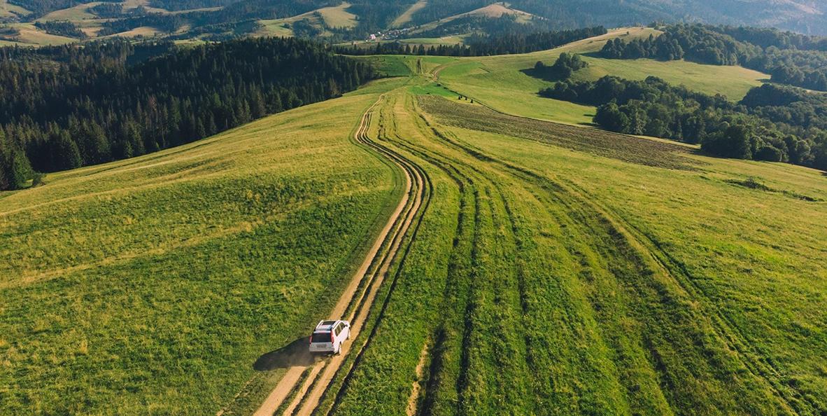Voiture roulant sur une route sur un champ à flanc de colline.