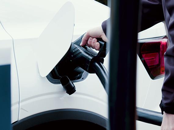 Quelqu'un remplissant sa batterie EV tenant une fiche.