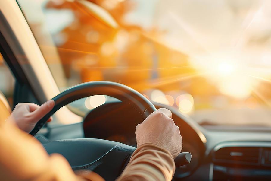 Personne conduisant une voiture au coucher du soleil.